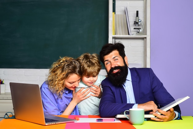 Carino allievo e suo padre e sua madre in classe scolaro felice alla lezione scuola di settembre