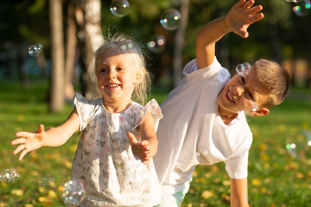 Carino bambini ragazzo e ragazza che soffiano bolle nel parco autunnale in giornata di sole.