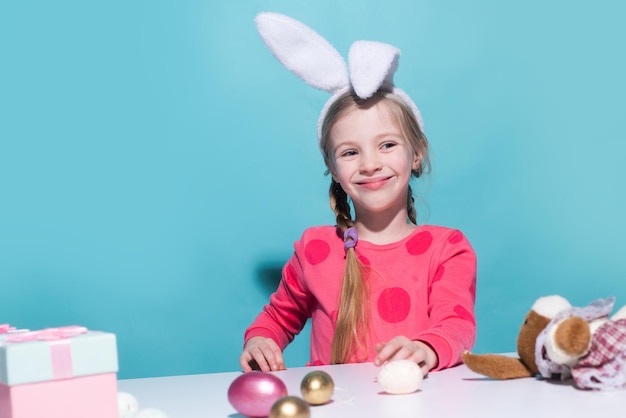 Carino bambino che indossa orecchie da coniglio il giorno di Pasqua Ragazza sorridente che tiene cesto con uova dipinte