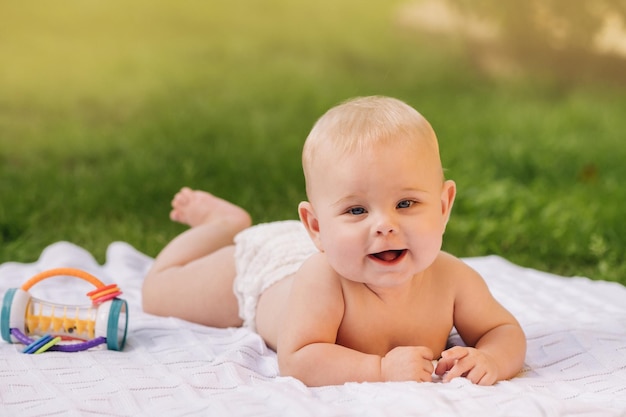 Carino bambino felice sdraiato su una coperta sull'erba all'aperto in estate