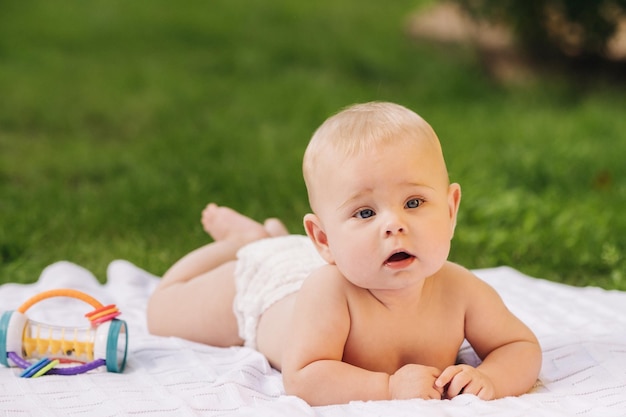 Carino bambino felice sdraiato su una coperta sull'erba all'aperto in estate