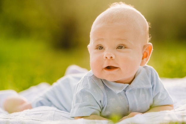 Carino bambino felice sdraiato su una coperta sull'erba all'aperto in estate