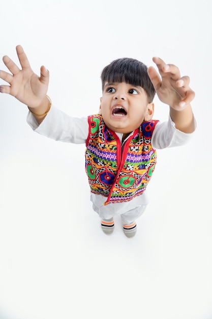 Carino bambino indiano in abbigliamento etnico e mostrando un'espressione testarda su sfondo bianco