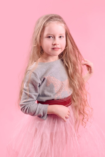 carino divertente bambina con lunghi capelli biondi su sfondo rosa