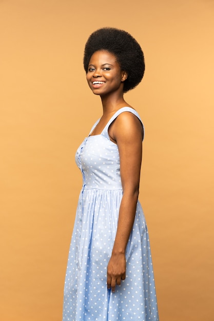 Carino donna afroamericana con bella acconciatura afro sorridente isolato beige studio background