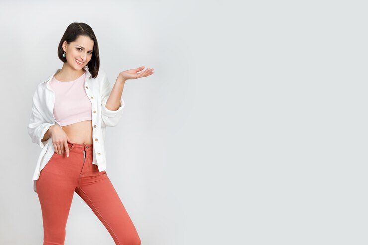 Carino donna bruna anni '30 in jeans corallo canotta rosa e camicia bianca su sfondo bianco