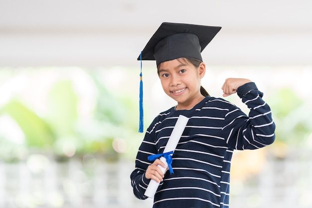 Carino felice ragazzo asiatico diplomato con cappello di laurea e un diploma isolato su sfondo bianco