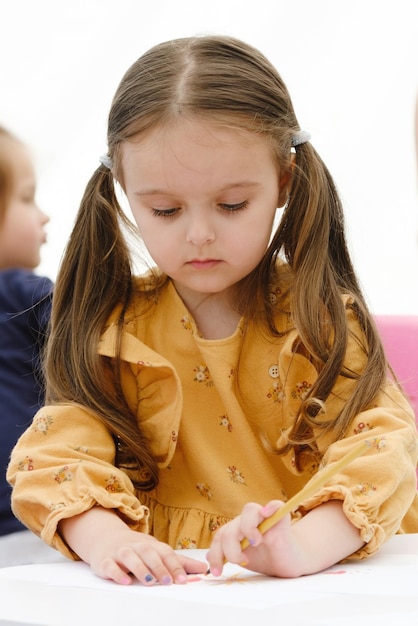 Carino giovane ragazza europea del bambino che dipinge con la matita colorata Concetto di educazione dei bambini dell'asilo