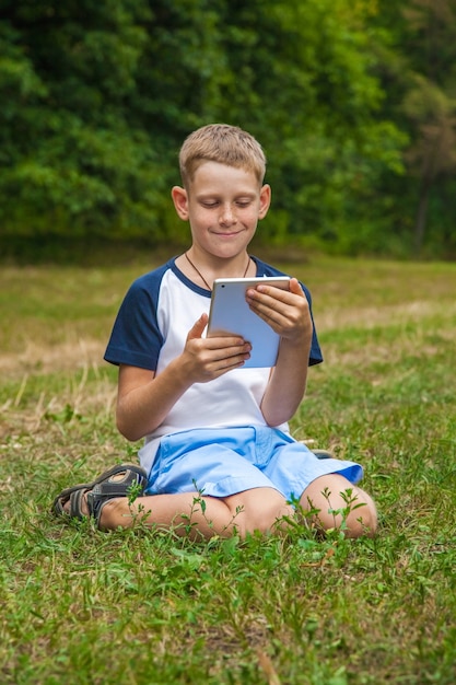 Carino giovane ragazzo caucasico che lavora con il tablet nel parco