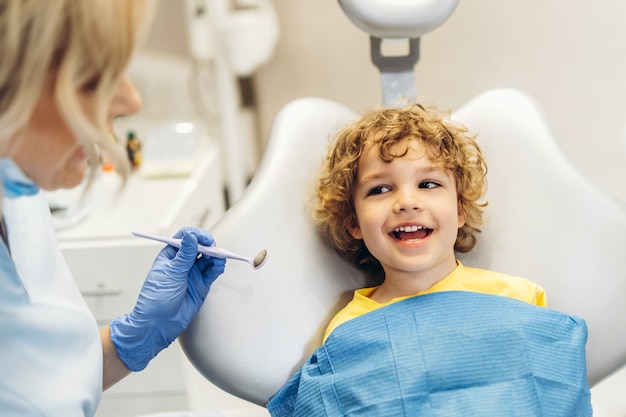 Carino giovane ragazzo in visita dal dentista e avendo i suoi denti controllati dal dentista femminile in studio dentistico