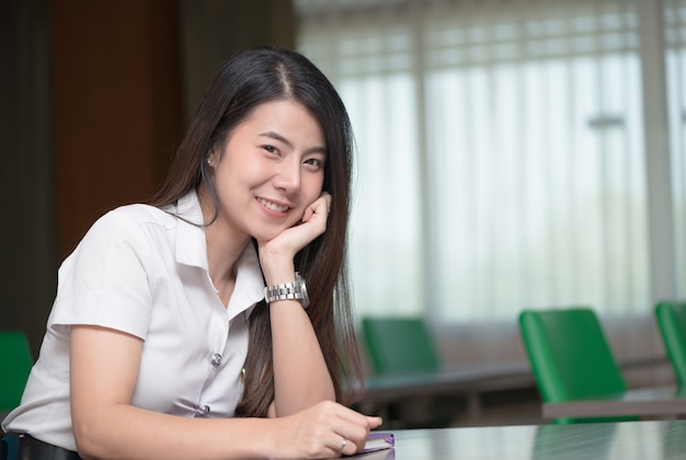 carino giovane studente asiatico in uniforme sorriso e sedersi in aula, educazione e concetto di apprendimento