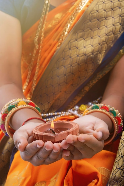 Carino indiano maharashtrian bambina che tiene la lampada in mano e celebra il tradizionale festival Raksha Bandhan o Diwali