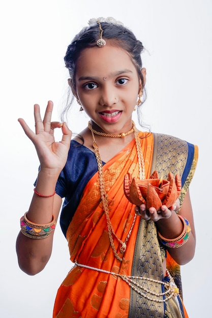 Carino indiano maharashtrian bambina che tiene la lampada in mano e celebra il tradizionale festival Raksha Bandhan o Diwali