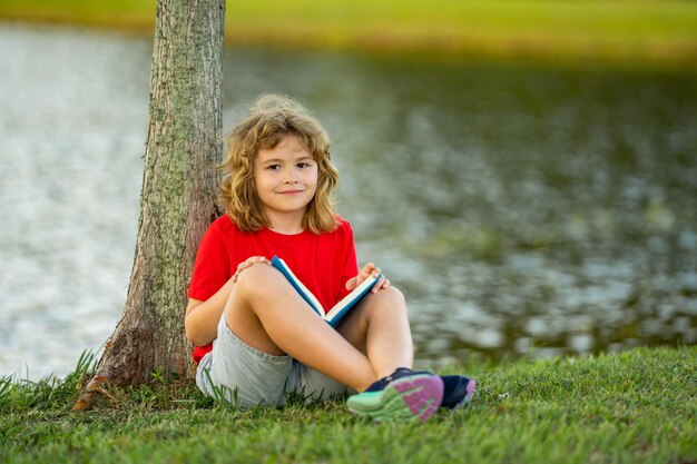 Carino libro di lettura per bambini sul prato all'aperto scuola e istruzione natura e parco apprendimento precoce poco