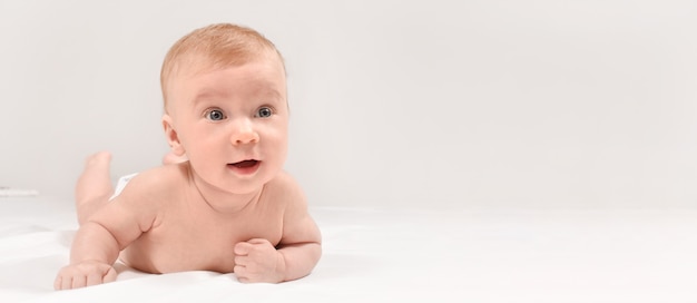 Carino mese nudo bambino sdraiato sullo stomak sorridente bella ragazza caucasica bionda con un sorriso adorabile