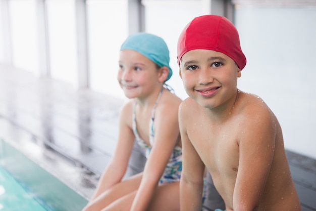 Carino piccoli bambini seduti a bordo piscina