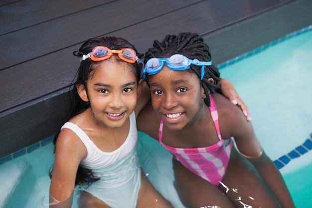 Carino piccoli bambini seduti a bordo piscina