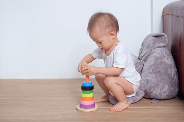Carino piccolo asiatico 18 mesi / 1 anno di età bambino bambino bambino gioca con piramide in legno colorato giocattolo / anello impilabile a