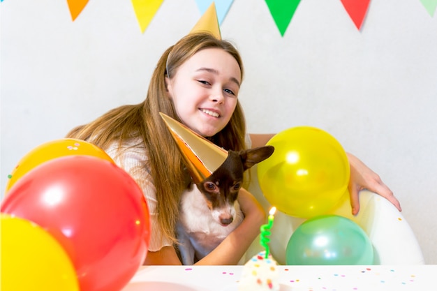Carino piccolo cane divertente con una torta di compleanno e un cappello da festa per festeggiare il compleanno