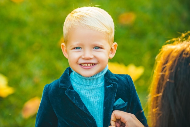 Carino piccolo ragazzo felice sorridente in tuta ritratto di bambino nel parco primaverile all'aperto primo piano faccia bambino pla