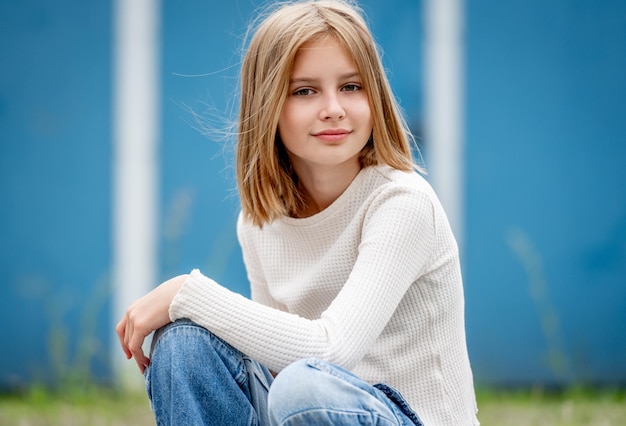 Carino preteen gitl con ritratto di capelli biondi Modello di ragazzo grazioso bambino seduto e guardando la fotocamera