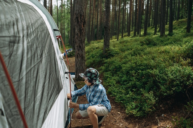 carino ragazzino caucasico che monta una tenda Concetto di campeggio familiare