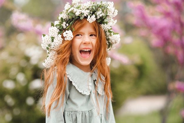 Carino ridendo ragazzino ragazza 3-4 anni indossare corona floreale e vestito rustico alla moda sulla natura