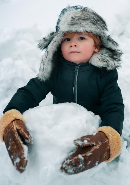 Carino ritratto invernale per bambini ritratto all'aperto di figlio piccolo in inverno freddo e soleggiato nel parco