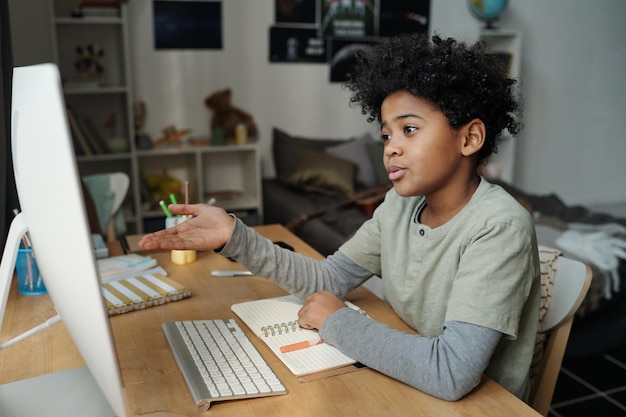 Carino scolaro che spiega qualcosa durante la comunicazione online