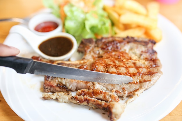 Carne alla griglia, bistecca di maiale con salsa al pepe e insalata.