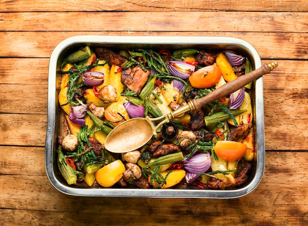 Carne alla griglia e verdure su fondo di legno rustico.Carne arrosto con verdure nel vassoio