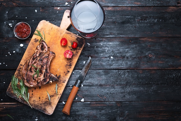 Carne alla griglia, menù di un ristorante, un bicchiere di vino rosso secco. Spezie ed erbe aromatiche.