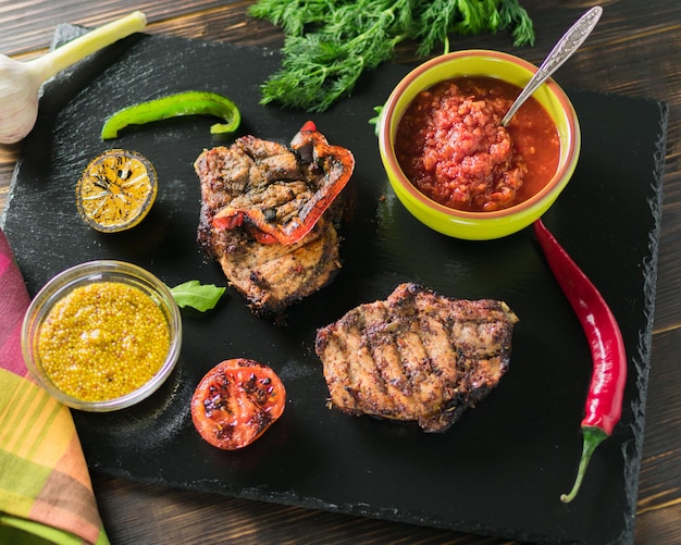 Carne alla griglia servita con spezie di verdure su un piatto di ardesia