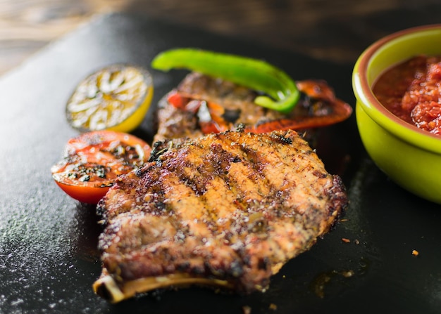 Carne alla griglia servita con spezie di verdure su un piatto di ardesia