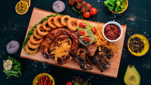 Carne alla griglia sulla tavola Costolette di salsiccia e verdure fresche su un tavolo di legno Vista dall'alto Spazio di copia