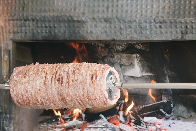 Carne allo spiedo vicino alla fornace del fuoco