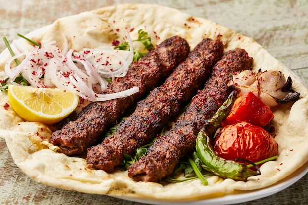 Carne araba Kabab con zafferano cipolla pomodoro pita pane fetta di limone e insalata servita in piatto isolato sul tavolo vista del cibo arabo