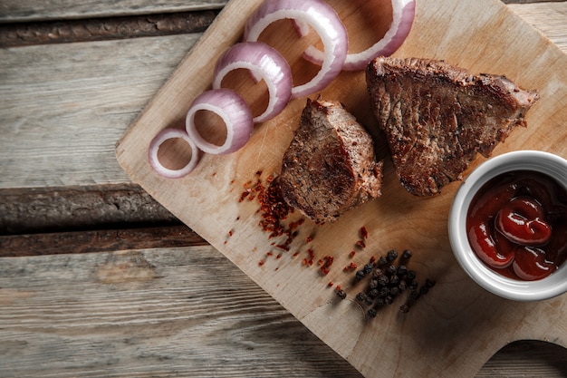 Carne arrostita con le spezie e la salsa al pomodoro su un fondo di legno consumato