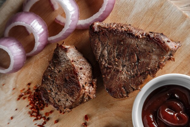 Carne arrostita con le spezie e la salsa al pomodoro su un fondo di legno consumato