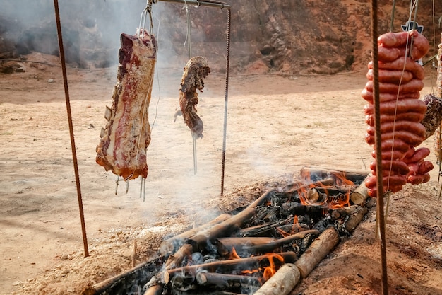 Carne arrosto e tagliata sul tavolo e fuoco di bivacco con legna da ardere in stile gaucho