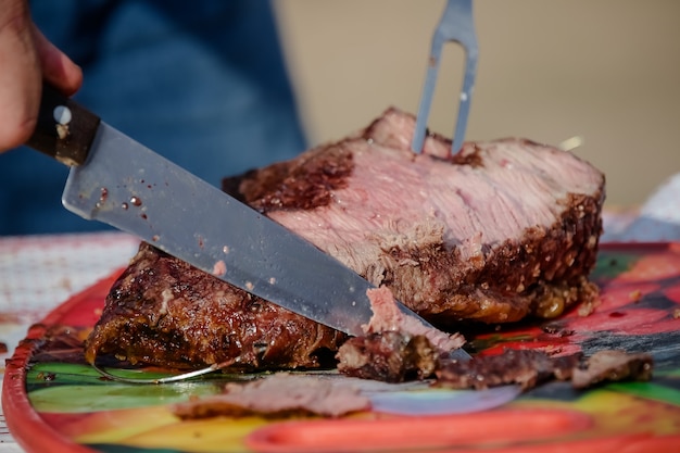 Carne arrosto e tagliata sul tavolo e fuoco di bivacco con legna da ardere in stile gaucho