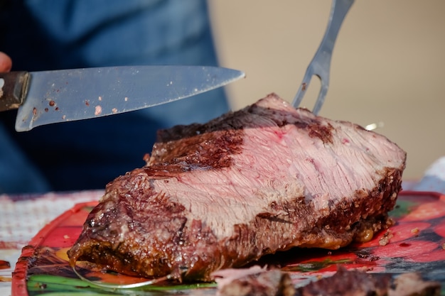 Carne arrosto e tagliata sul tavolo e fuoco di bivacco con legna da ardere in stile gaucho