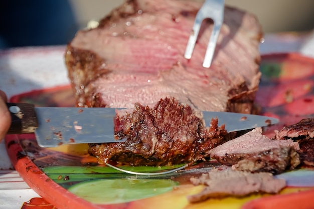 Carne arrosto e tagliata sul tavolo e fuoco di bivacco con legna da ardere in stile gaucho