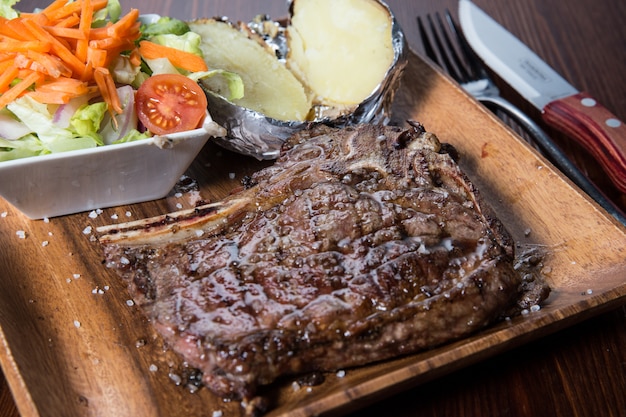 Carne con verdure su un piatto di legno