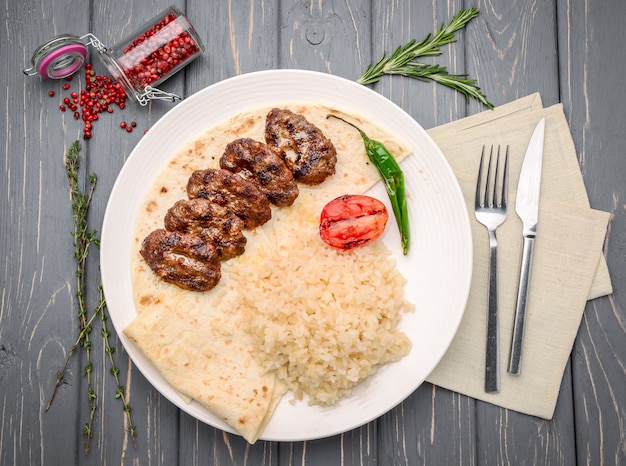 Carne cotta, riso bianco e verdure sulla tavola di legno