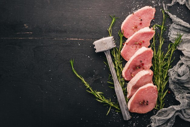 Carne cruda Bistecca di manzo con rosmarino e spezie su fondo di legno nero Vista dall'alto Spazio libero per il testo