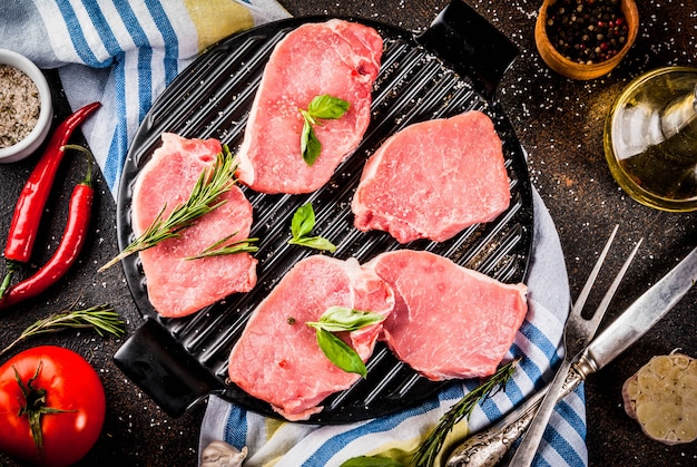 Carne cruda, bistecche di maiale con spezie, erbe aromatiche, olio d'oliva,