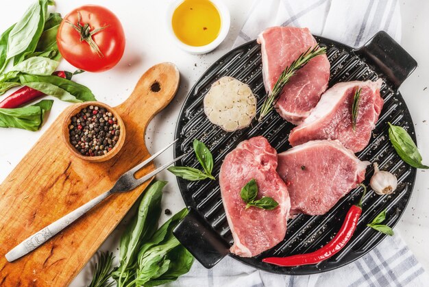 Carne cruda, bistecche di maiale con spezie, erbe aromatiche, olio d'oliva