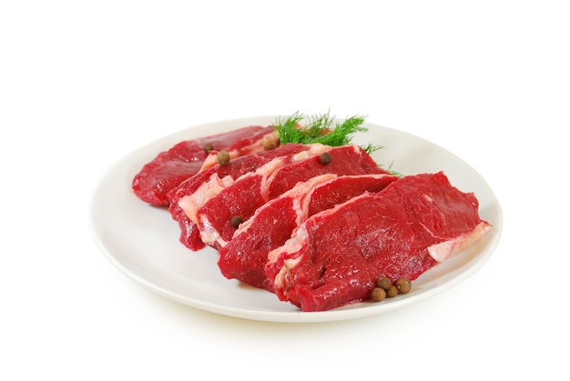 Carne cruda. Bistecche di manzo o di vitello con aneto in un piatto isolato su sfondo bianco