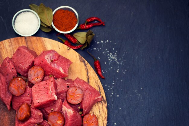 Carne cruda con salsiccia affumicata sul bordo di legno